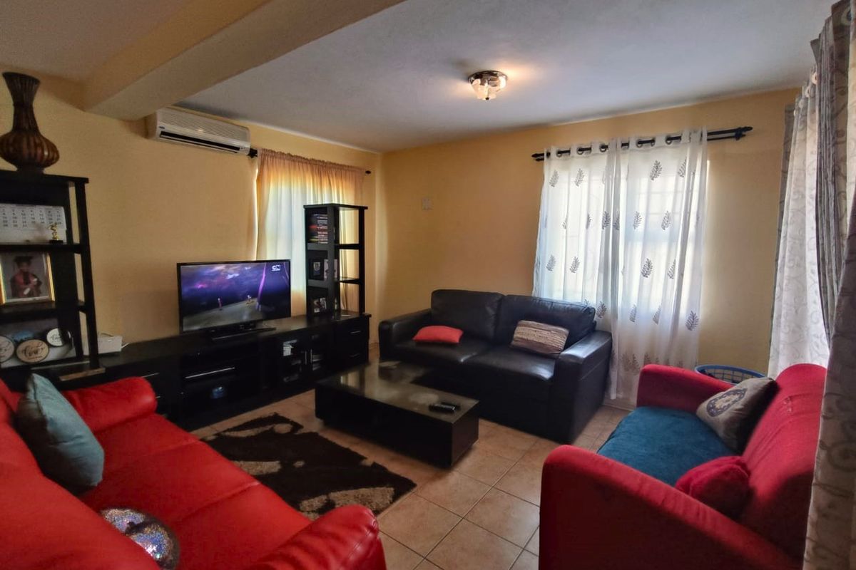 A comfortable living room featuring tiled flooring and a wall-mounted split-system air conditioner, providing a functional space for relaxation.