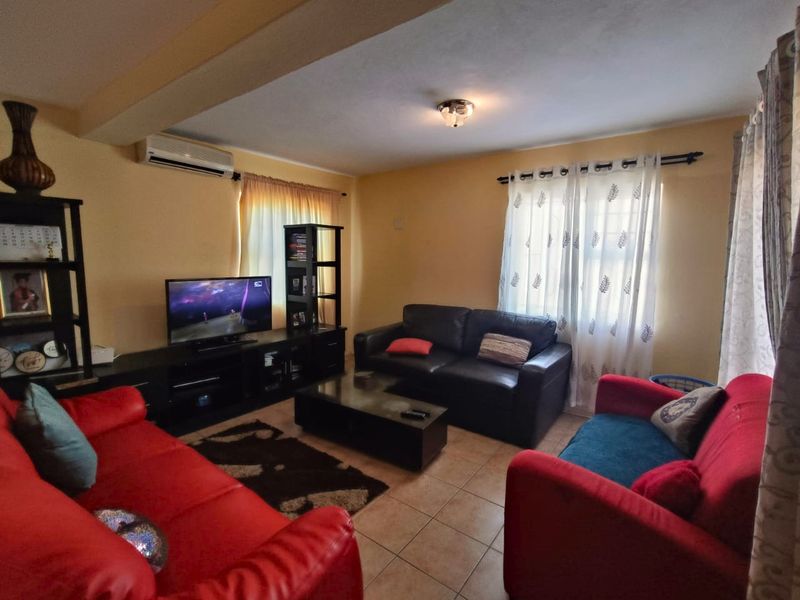 A comfortable living room featuring tiled flooring and a wall-mounted split-system air conditioner, providing a functional space for relaxation.