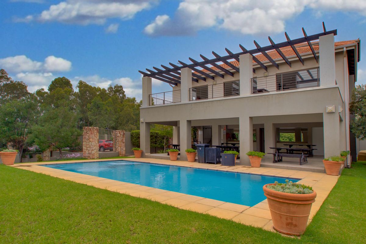 A spacious rear exterior view featuring a swimming pool, a covered patio area, and a balcony with a pergola structure.