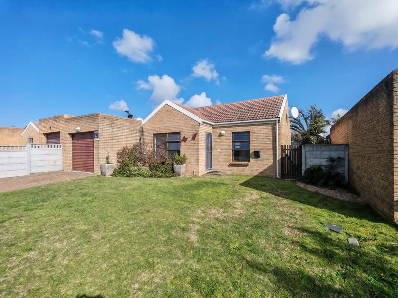 Front view of a face brick house featuring a tiled roof, attached garage with a roller door, and a front garden with a paved driveway.