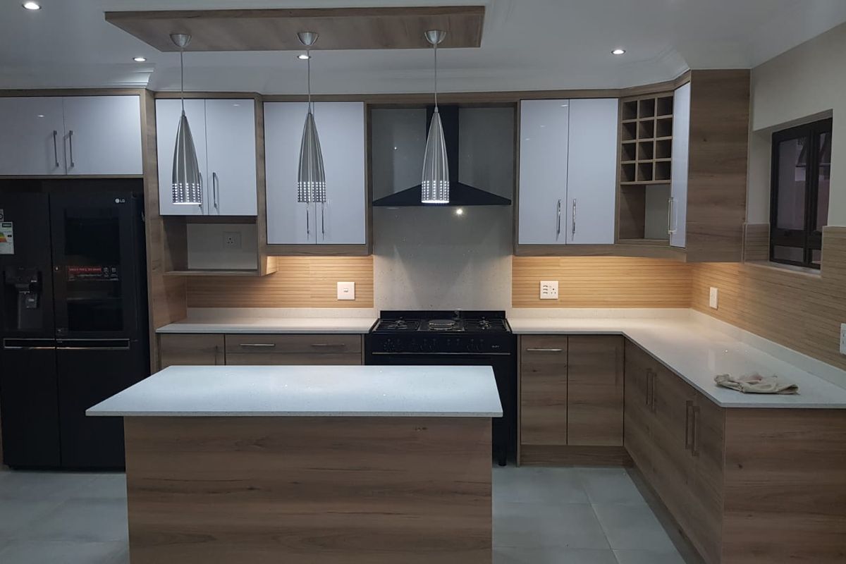 Modern kitchen featuring wood-grain cabinetry, white stone countertops, a central island, and integrated extractor fan with recessed ceiling lighting.