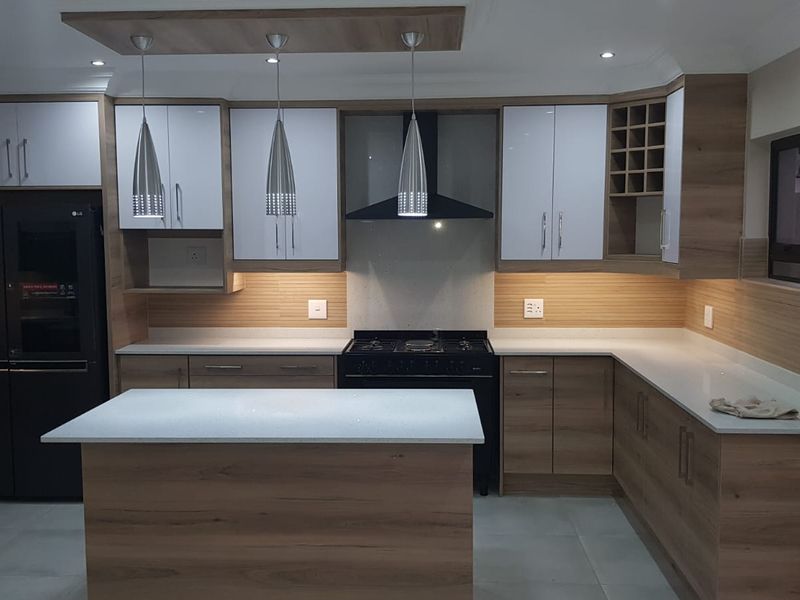 Modern kitchen featuring wood-grain cabinetry, white stone countertops, a central island, and integrated extractor fan with recessed ceiling lighting.