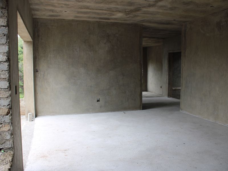 An unfinished interior space in shell condition, featuring raw concrete walls, exposed masonry, and concrete flooring, ready for final fit-out and finishes.