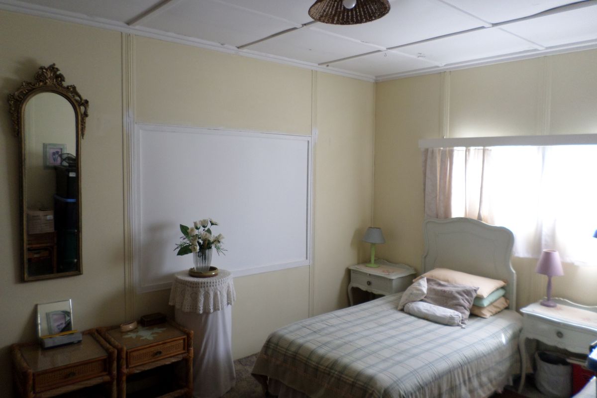 A bedroom featuring a tiled ceiling and natural light from the window, currently requiring cosmetic updates to the wall finishes.
