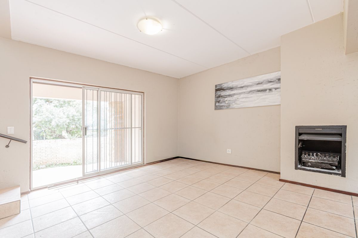 An open-plan living area featuring tiled flooring, a built-in fireplace, and sliding glass doors providing access to an outdoor patio.