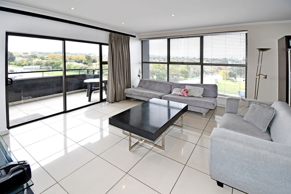 Spacious living area featuring large floor-to-ceiling windows, polished tile flooring, recessed lighting, and direct access to a private balcony with scenic views.