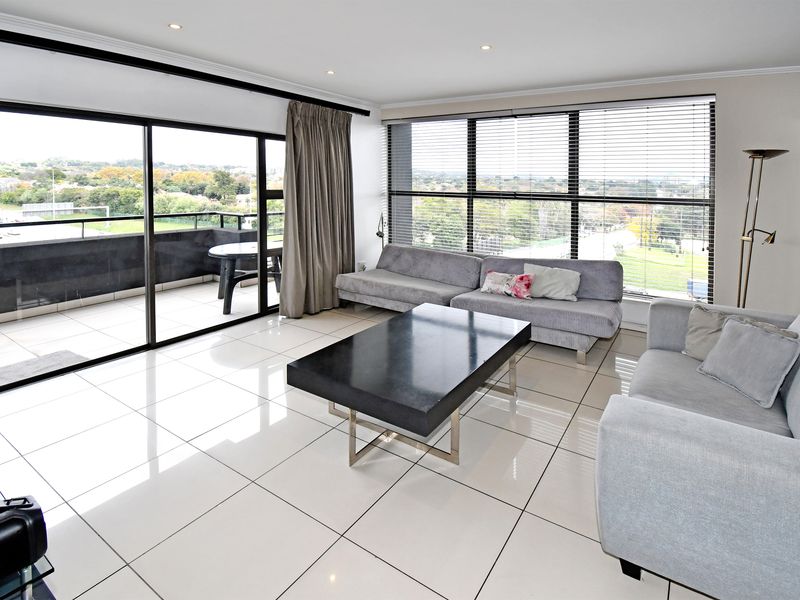 Spacious living area featuring large floor-to-ceiling windows, polished tile flooring, recessed lighting, and direct access to a private balcony with scenic views.
