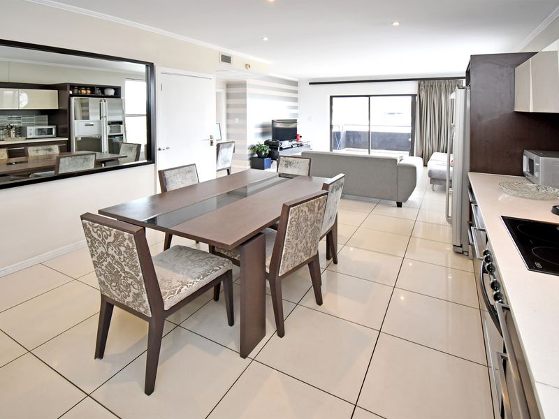 Open-plan living and dining area featuring tiled flooring, a modern kitchen with built-in cabinetry, and direct access to a private balcony.