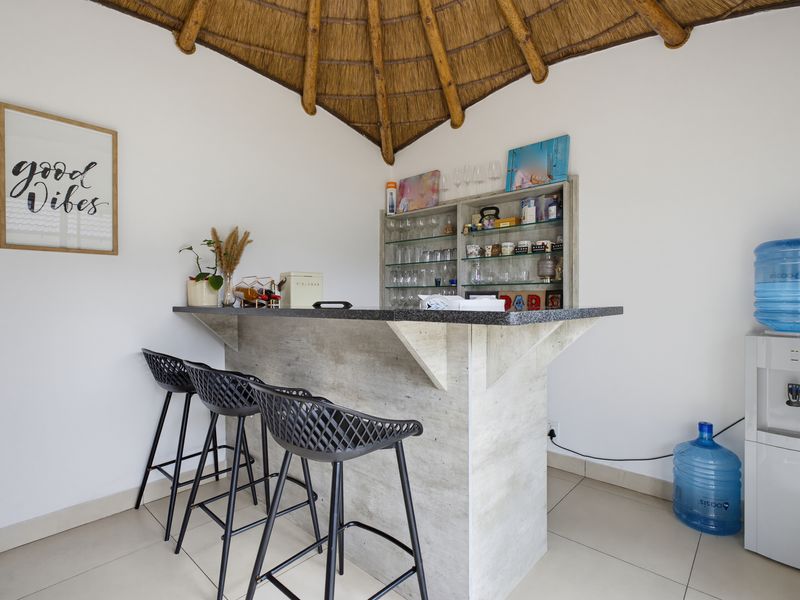 A built-in bar area featuring a stone-look counter, integrated shelving, and a distinctive thatched roof ceiling detail.