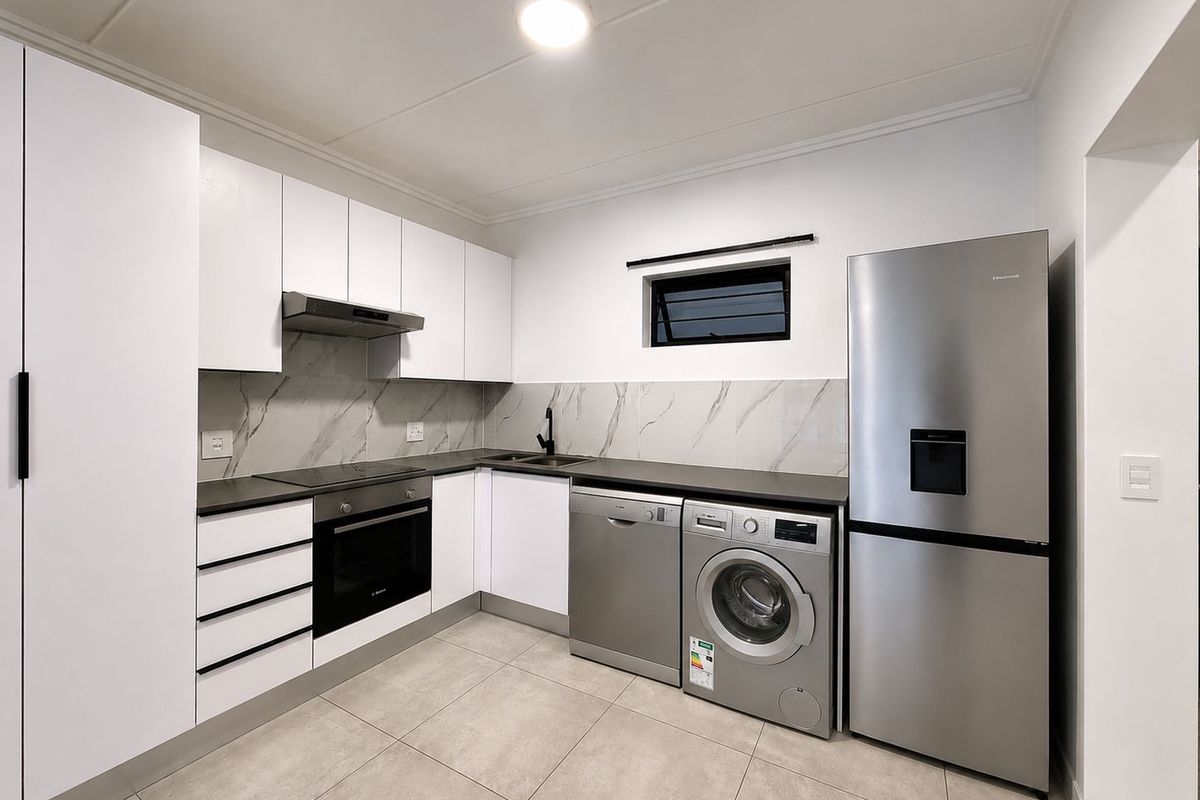 Modern kitchen featuring white cabinetry, marble-look splashback, dark countertops, and integrated stainless steel appliances including an oven, hob, and extractor fan.
