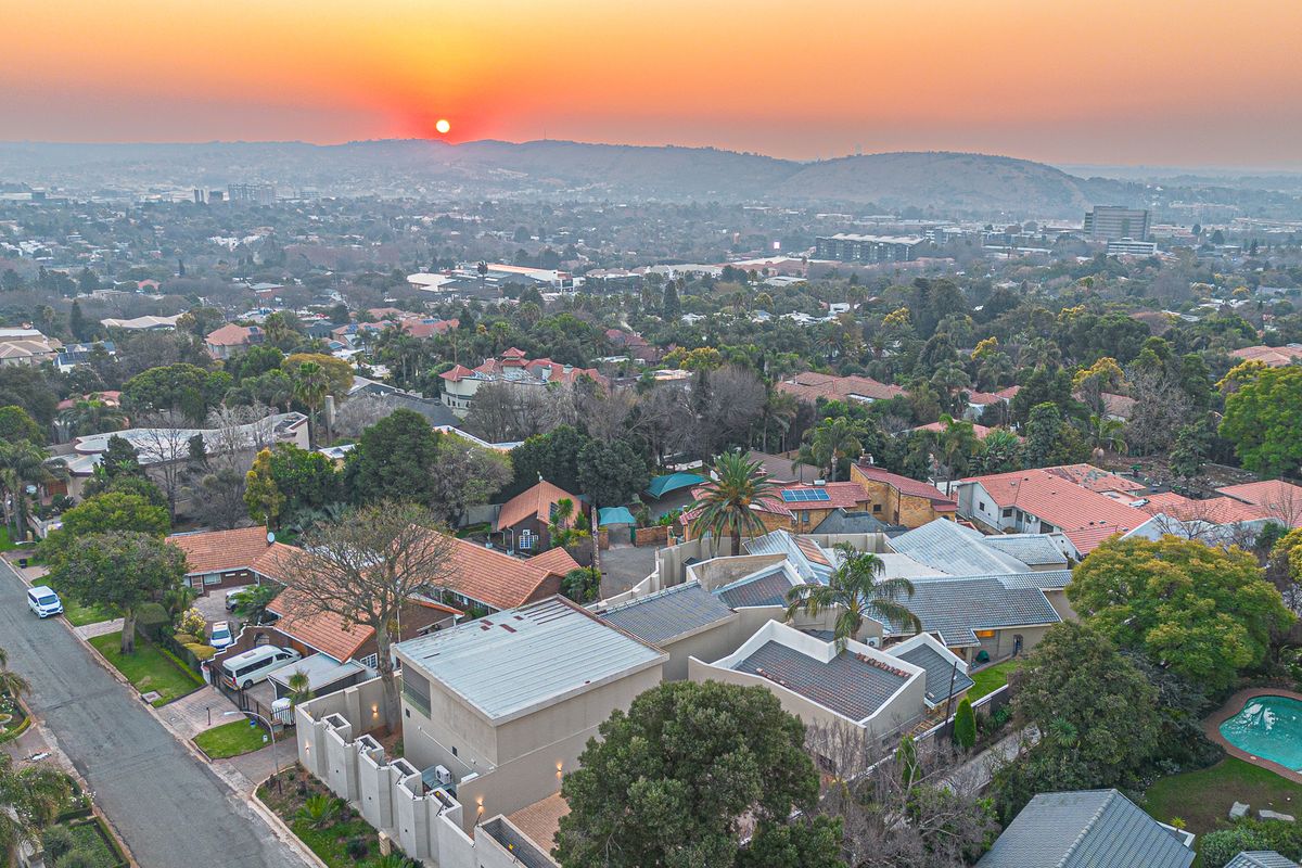 An elevated aerial view of a residential neighborhood at sunset, showcasing the property's location, surrounding homes, and local landscape.