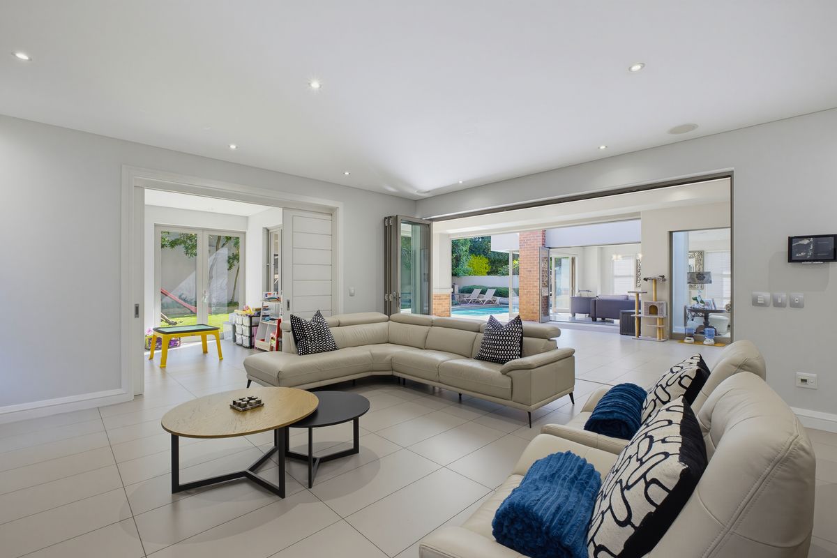 Spacious open-plan living area featuring large format floor tiles, recessed lighting, and seamless indoor-outdoor flow through expansive stacking glass doors.