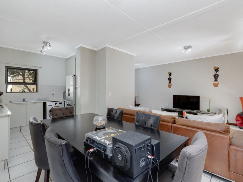 Open-plan living area featuring a functional kitchen with built-in cabinetry, tiled flooring, and a combined dining and lounge space.