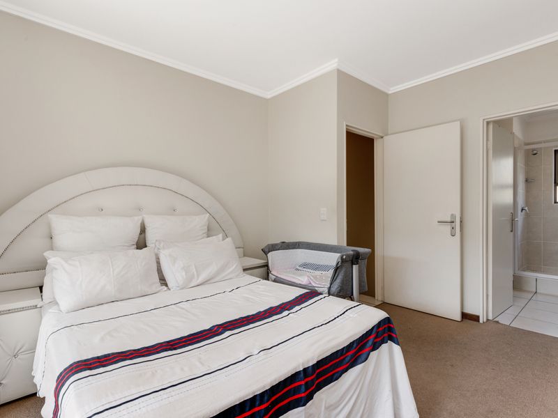 A well-maintained bedroom featuring neutral wall tones, carpeted flooring, coved ceilings, and direct access to an en-suite bathroom.