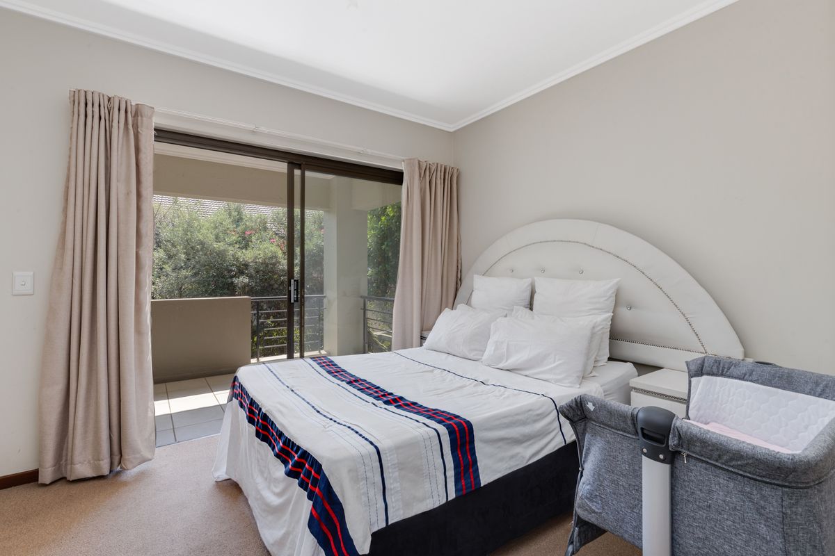 A well-maintained bedroom featuring neutral walls, carpeted flooring, and a sliding glass door providing access to a private balcony.