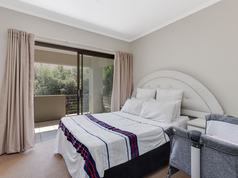 A well-maintained bedroom featuring neutral walls, carpeted flooring, and a sliding glass door providing access to a private balcony.