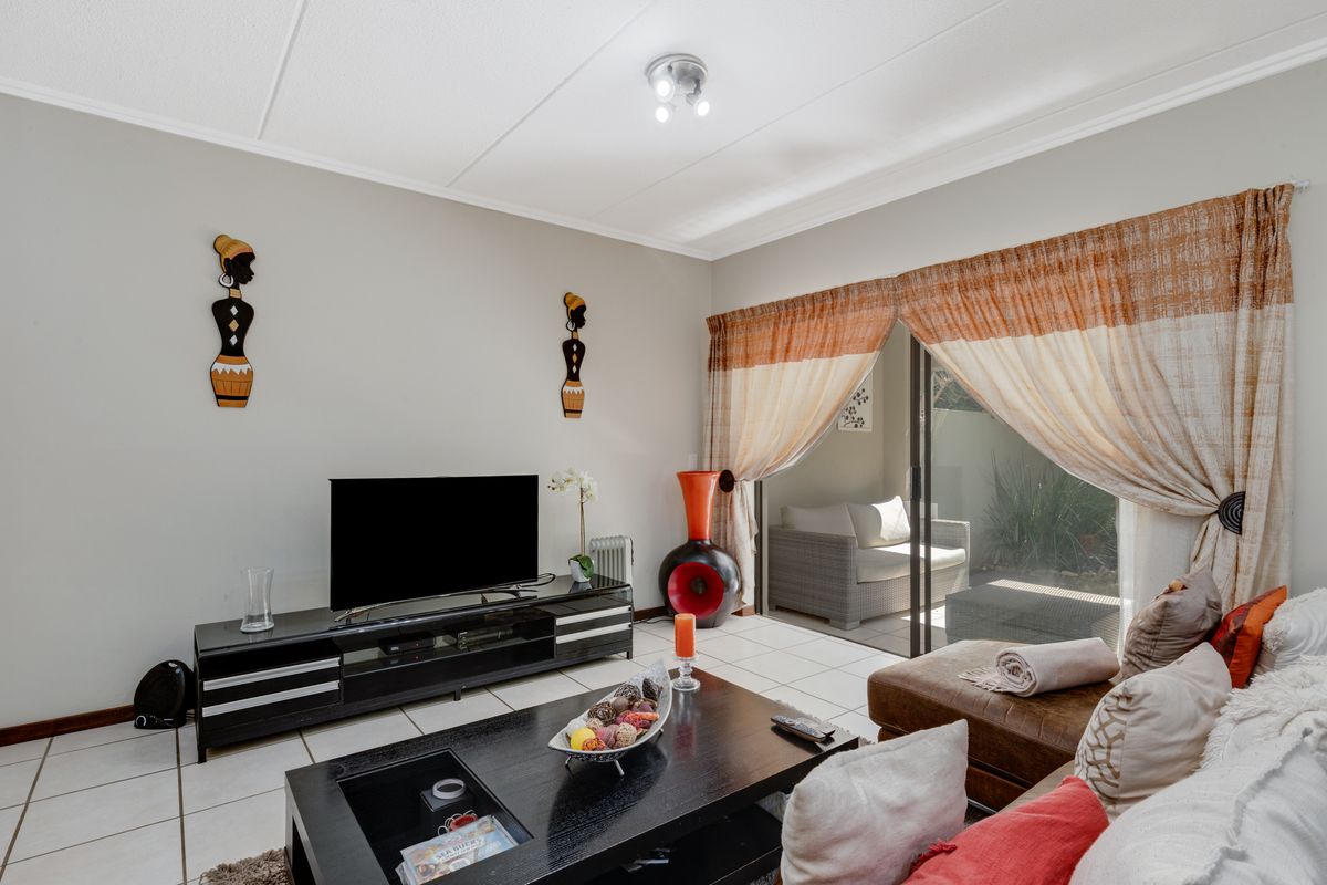A comfortable living room featuring tiled flooring and a large sliding glass door that provides direct access to the outdoor patio area.