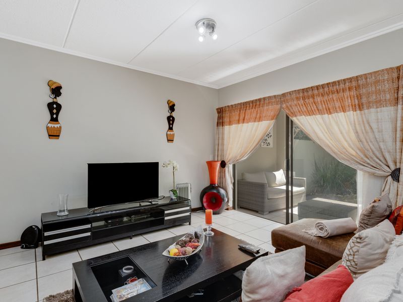 A comfortable living room featuring tiled flooring and a large sliding glass door that provides direct access to the outdoor patio area.