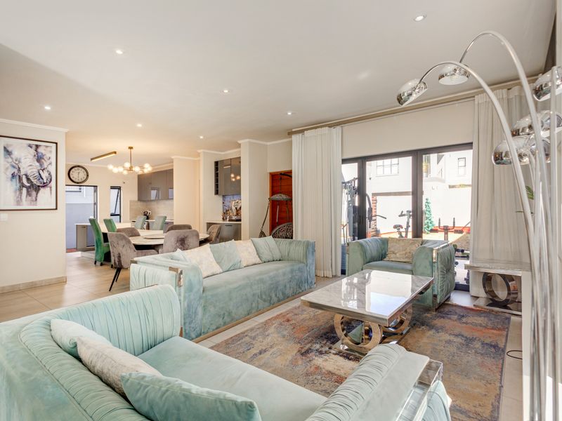 Spacious open-plan living and dining area featuring modern tiled flooring, recessed lighting, and large sliding glass doors leading to the outdoor space.