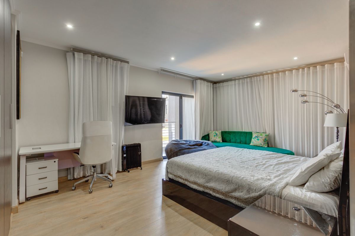 A well-maintained bedroom featuring laminate flooring, recessed downlighting, and a sliding glass door providing access to an outdoor area.