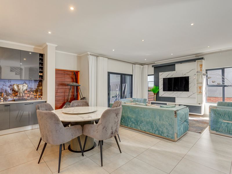 Spacious open-plan living and dining area featuring modern tiled floors, recessed lighting, and a custom built-in media wall with integrated cabinetry.