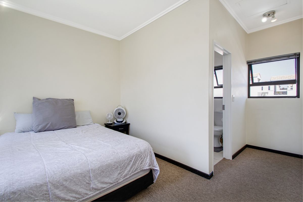 A functional bedroom featuring neutral walls, carpeted flooring, and direct access to an en-suite bathroom.