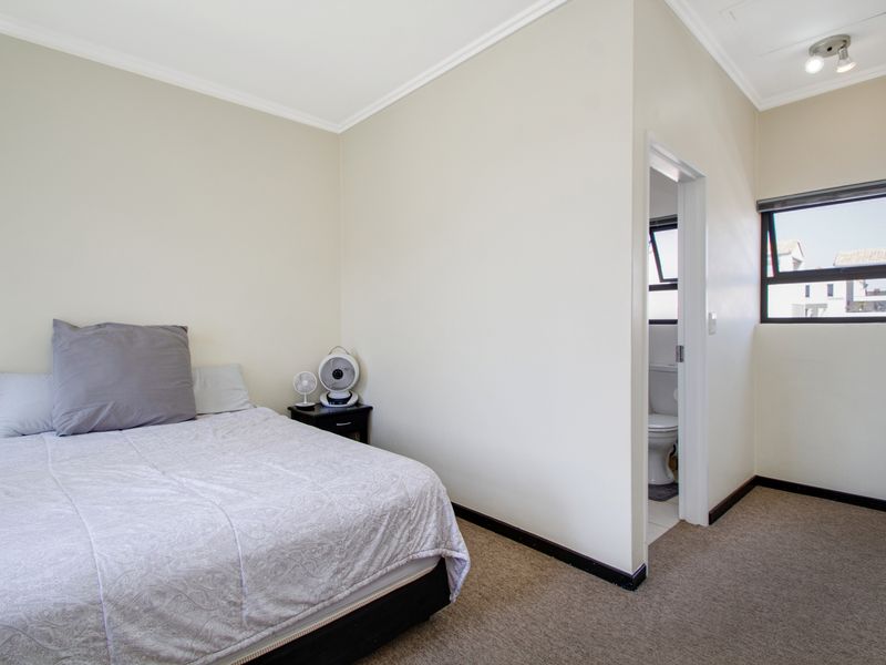 A functional bedroom featuring neutral walls, carpeted flooring, and direct access to an en-suite bathroom.