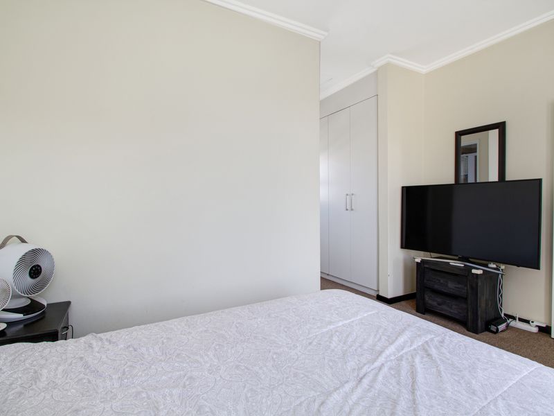 A well-maintained bedroom featuring neutral walls, carpeted flooring, and built-in cupboards providing ample storage space.