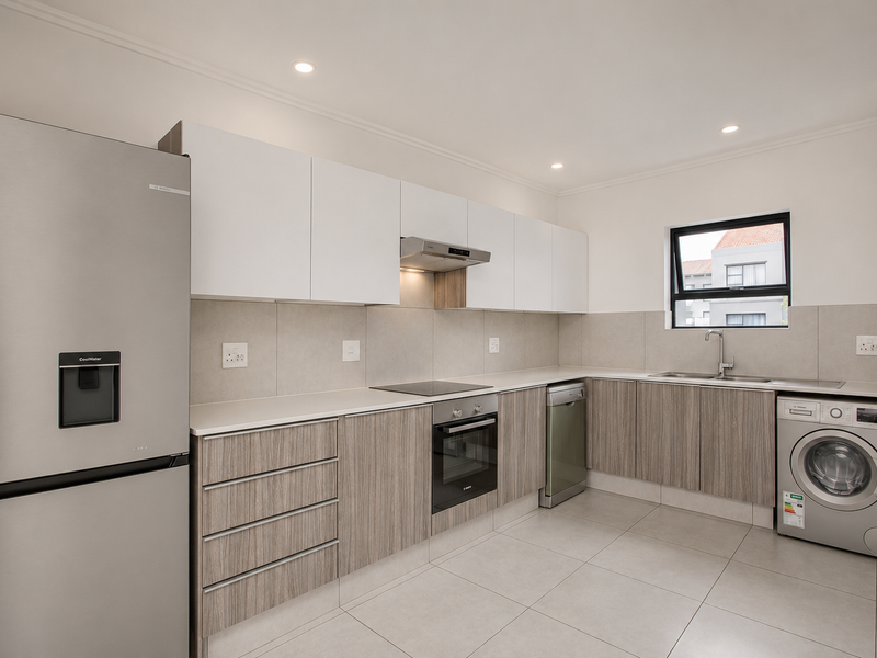 Modern kitchen featuring sleek two-tone cabinetry, stone countertops, integrated appliances, and high-quality tiled flooring in a clean, contemporary design.