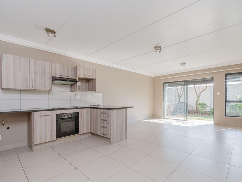 Spacious open-plan kitchen and living area featuring modern cabinetry, built-in oven, tiled flooring, and direct access to a private outdoor patio through sliding doors.