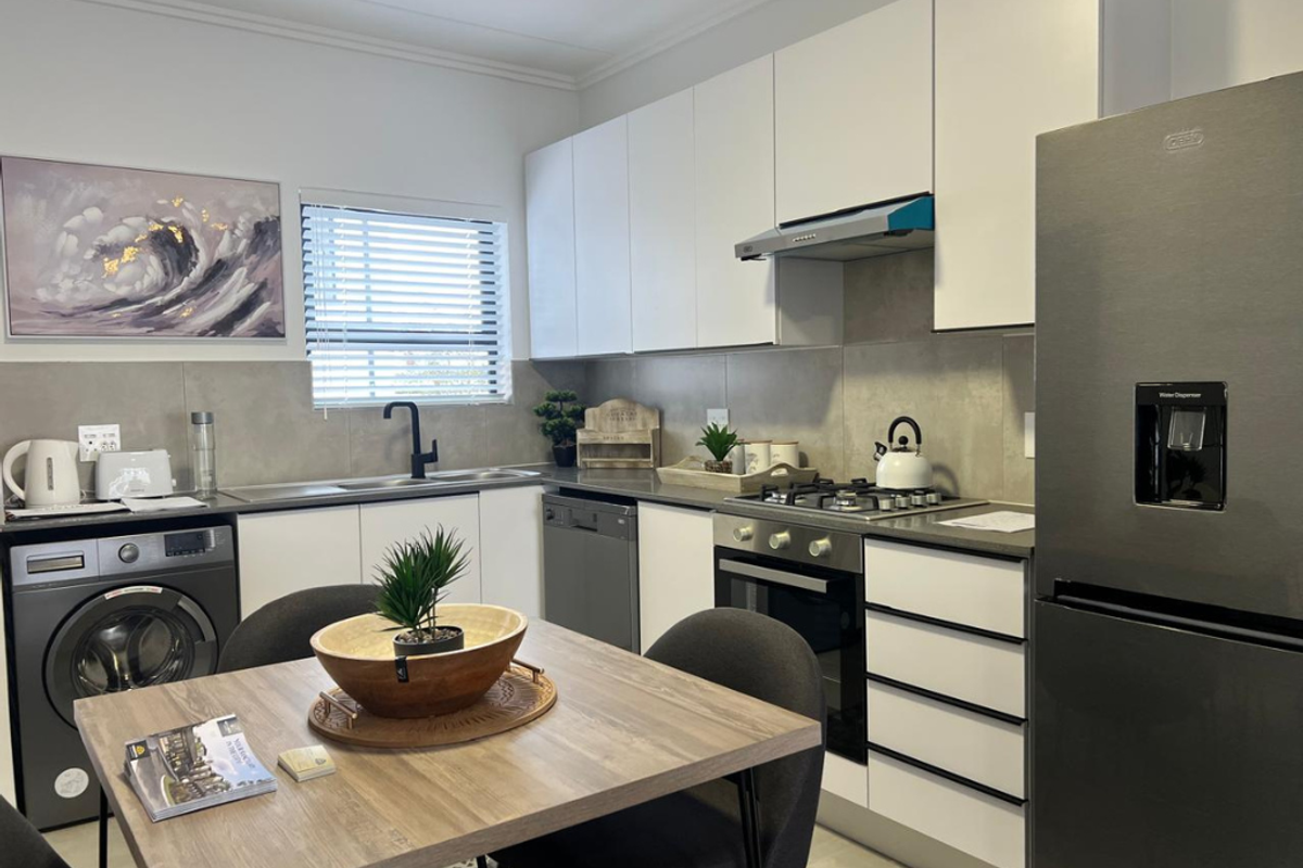 Modern kitchen featuring sleek white cabinetry, stone-look splashback, gas hob, built-in oven, and integrated dishwasher, offering a clean and functional culinary space.