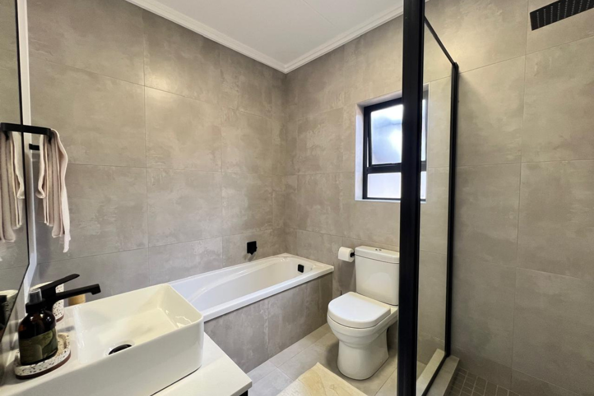 Modern bathroom featuring a built-in bathtub, a separate walk-in shower with a black frame, and a contemporary basin.