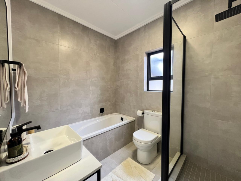 Modern bathroom featuring a built-in bathtub, a separate walk-in shower with a black frame, and a contemporary basin.