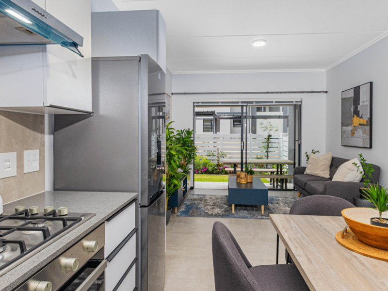 Modern open-plan living area featuring a well-appointed kitchen with gas hob, stone countertops, and seamless flow to an outdoor patio through sliding glass doors.
