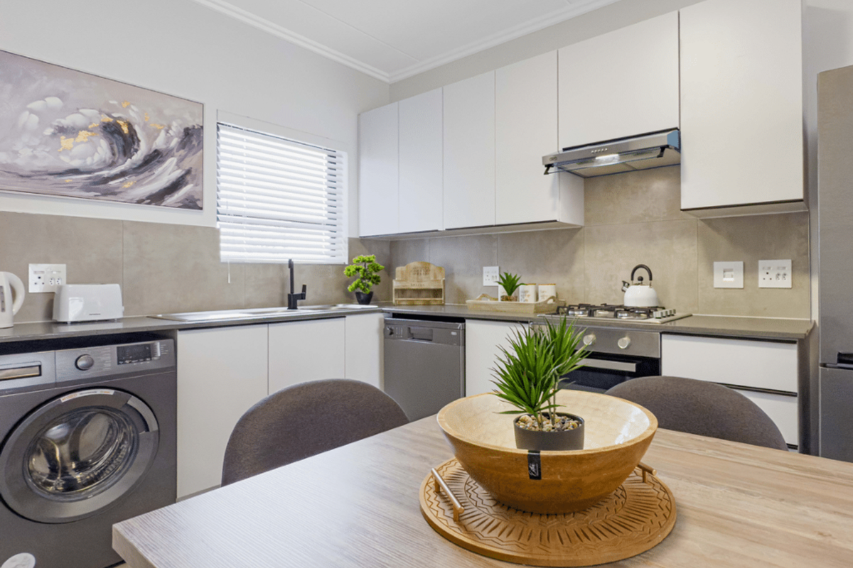 Modern kitchen featuring sleek white cabinetry, stone-look countertops, integrated appliances, and a tiled backsplash, offering a clean and functional culinary space.