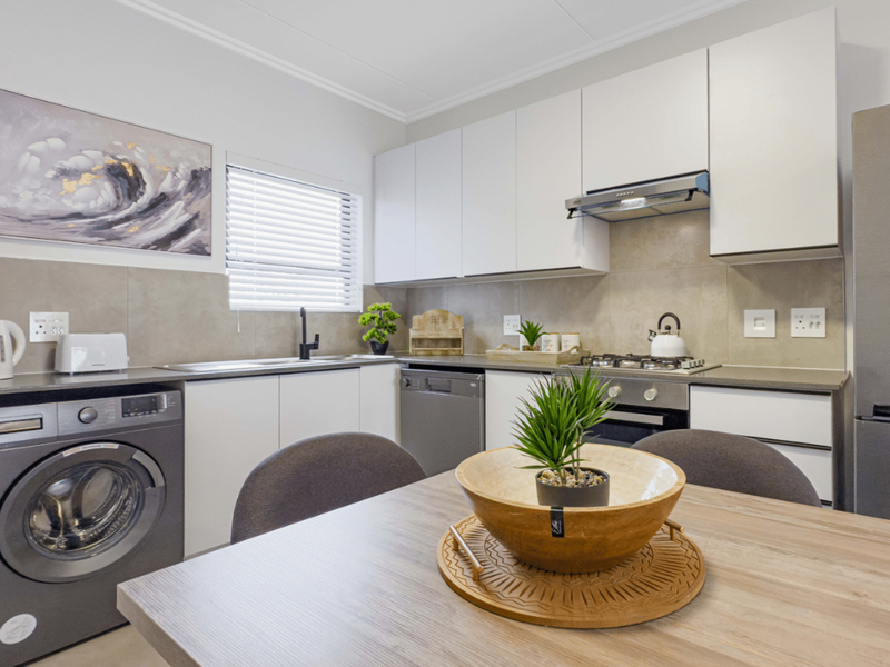 Modern kitchen featuring sleek white cabinetry, stone-look countertops, integrated appliances, and a tiled backsplash, offering a clean and functional culinary space.