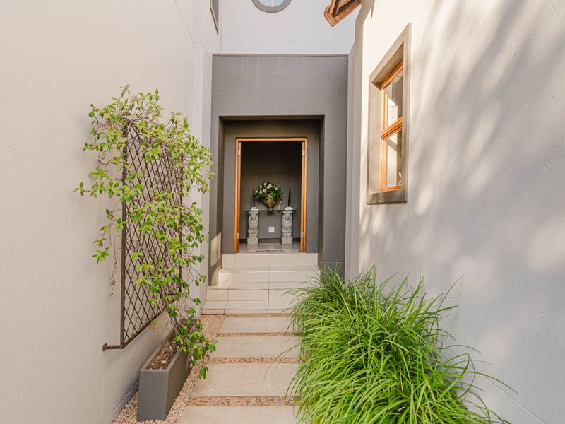 A welcoming, modern entrance featuring a tiled walkway leading to a recessed doorway with clean architectural lines and neutral exterior finishes.