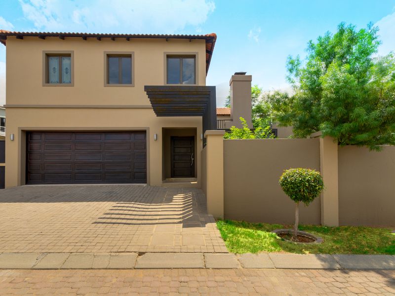 Front elevation of a modern cluster home featuring a double garage, paved driveway, and a contemporary pergola entrance.