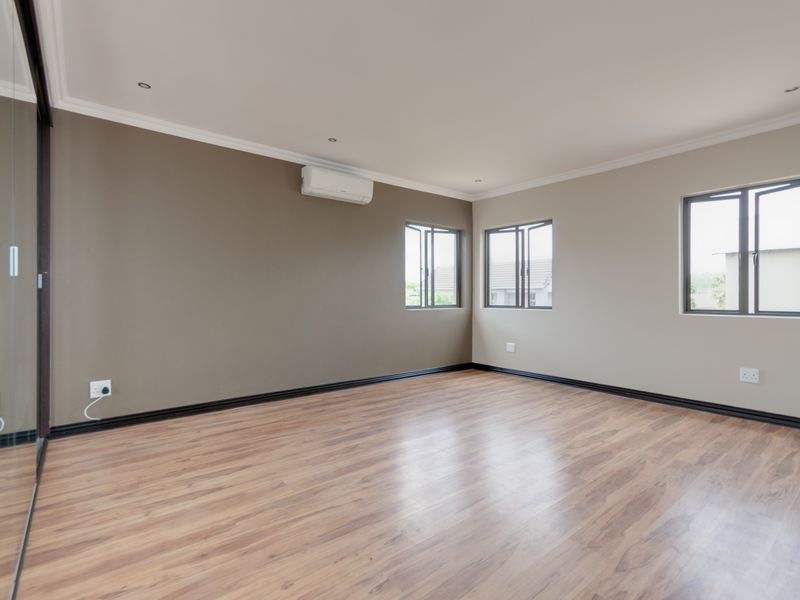 Spacious, empty bedroom featuring laminate flooring, neutral wall tones, recessed lighting, and a wall-mounted air conditioning unit.
