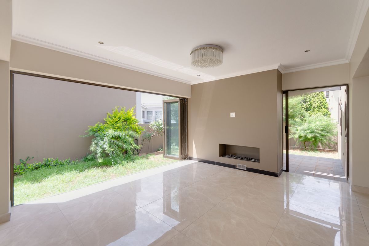 Spacious living area featuring polished porcelain tiles, a modern recessed fireplace, and large bi-fold doors opening onto a private garden space.