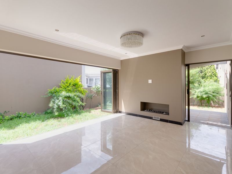 Spacious living area featuring polished porcelain tiles, a modern recessed fireplace, and large bi-fold doors opening onto a private garden space.