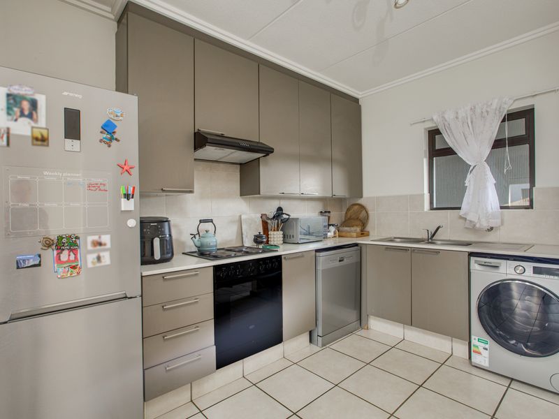 A functional kitchen featuring modern grey cabinetry, tiled backsplash, built-in oven and hob, and integrated laundry and dishwasher appliances.