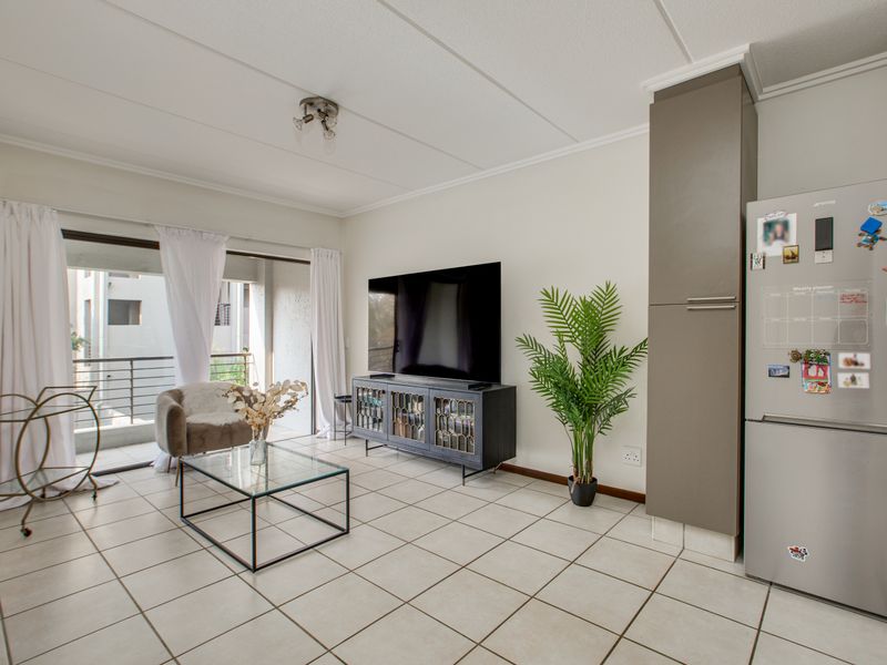 Open-plan living area featuring tiled flooring and direct access to a private balcony through large sliding glass doors.