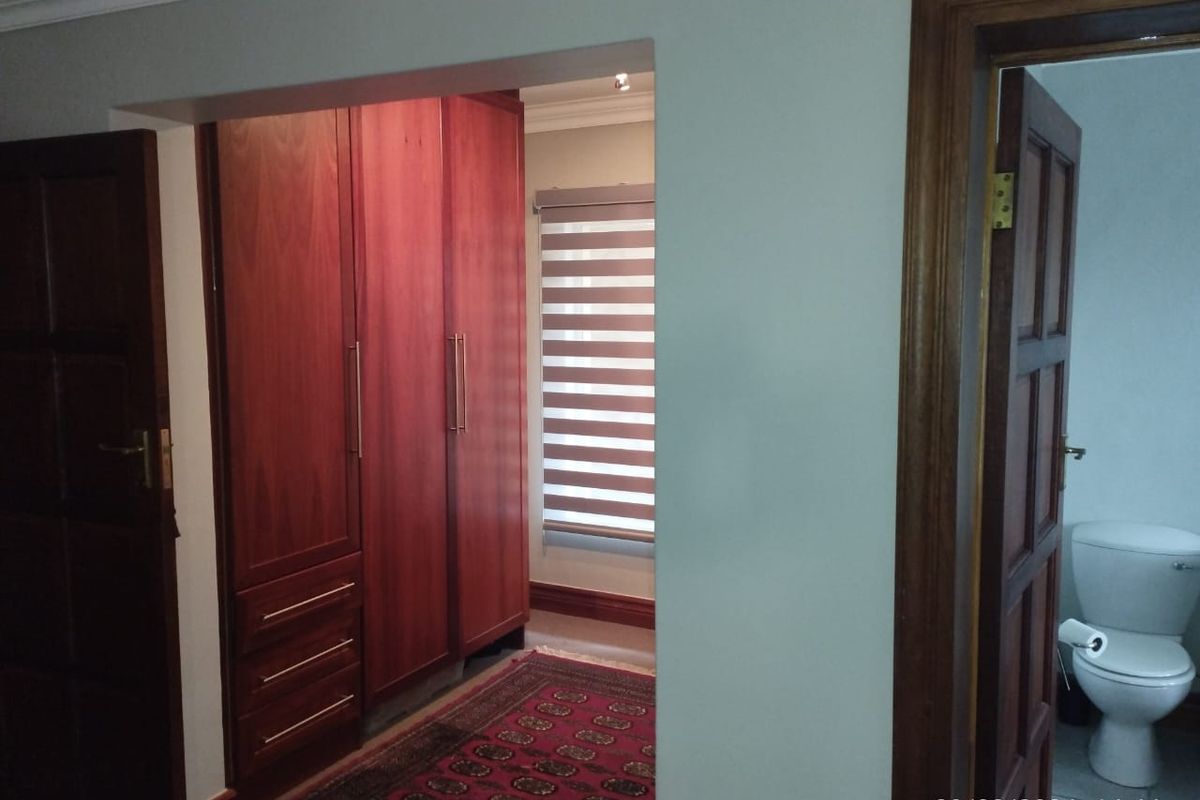 A bedroom area featuring built-in wooden cabinetry and a view into an adjacent bathroom with a toilet.