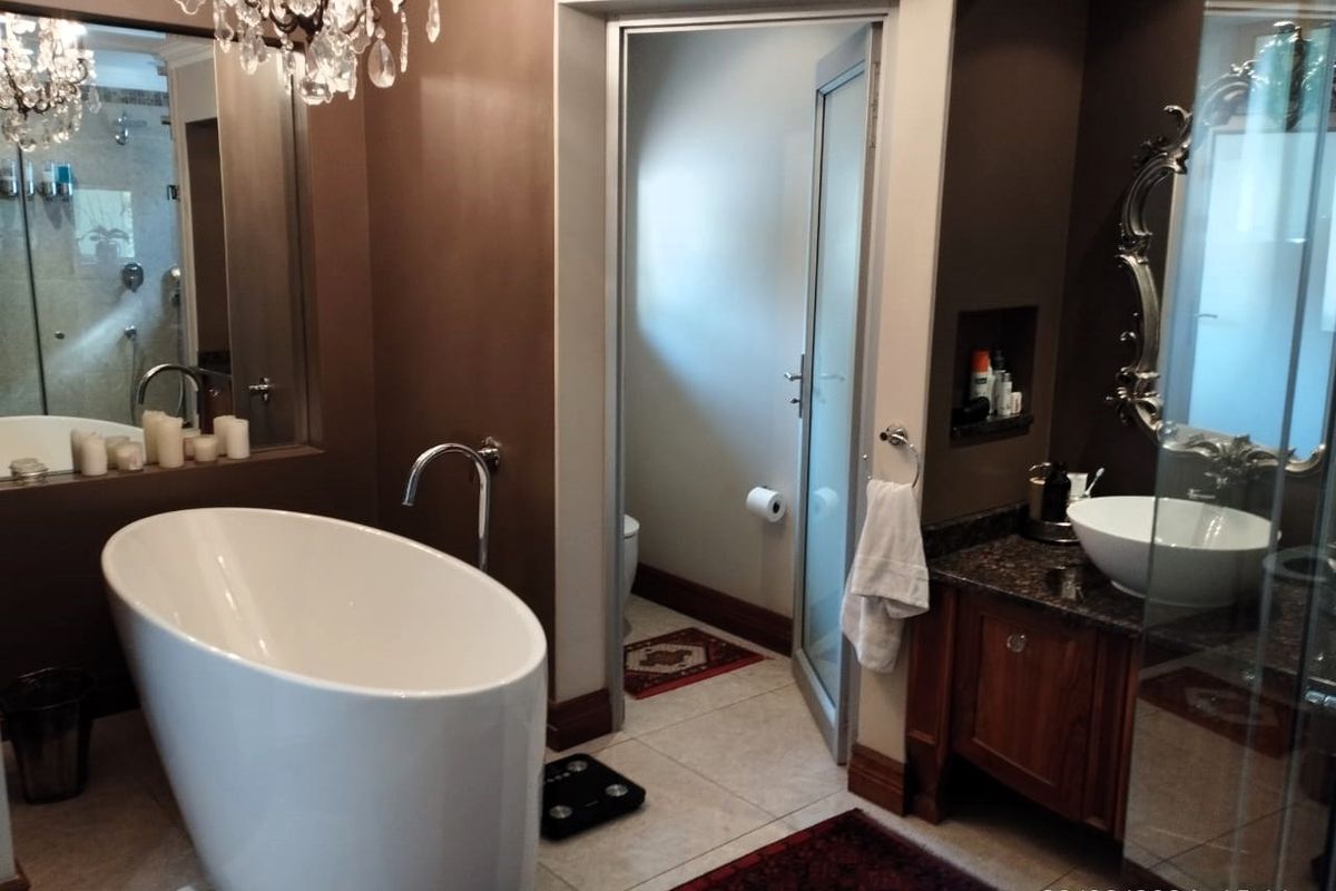 A well-appointed bathroom featuring a modern freestanding bathtub, a vanity with a granite countertop and vessel sink, and a separate enclosed toilet area.