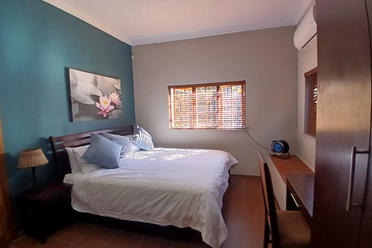 A well-maintained bedroom featuring tiled flooring, built-in cabinetry, an air conditioning unit, and wooden blinds for privacy.