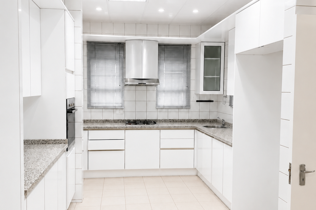 A clean, well-lit kitchen featuring white cabinetry, granite countertops, built-in oven, gas hob, and tiled flooring.