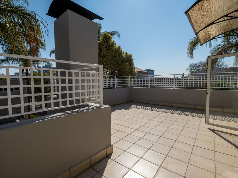 Spacious open-air balcony featuring a built-in braai, tiled flooring, and secure metal balustrades, perfect for outdoor entertaining.
