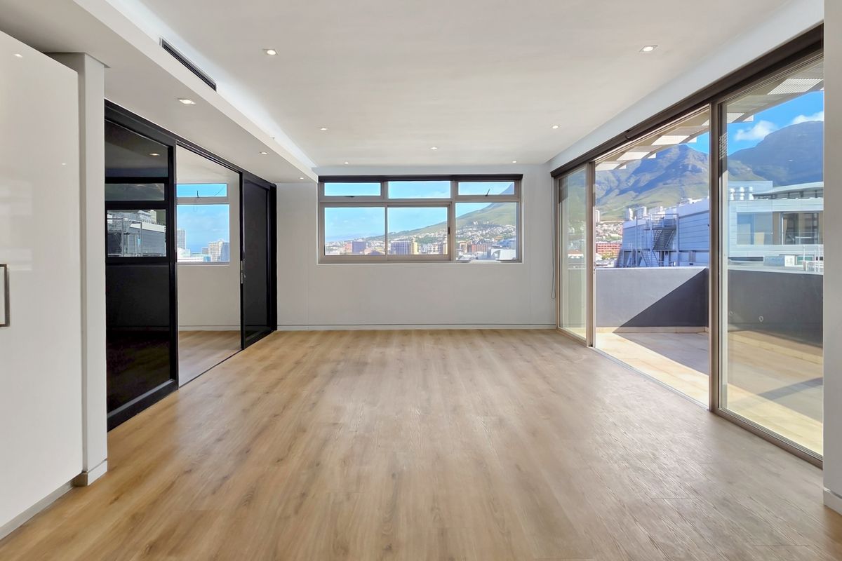 Spacious, light-filled living area featuring modern laminate flooring, recessed lighting, ducted air conditioning, and large sliding doors opening to a private balcony with mountain views.