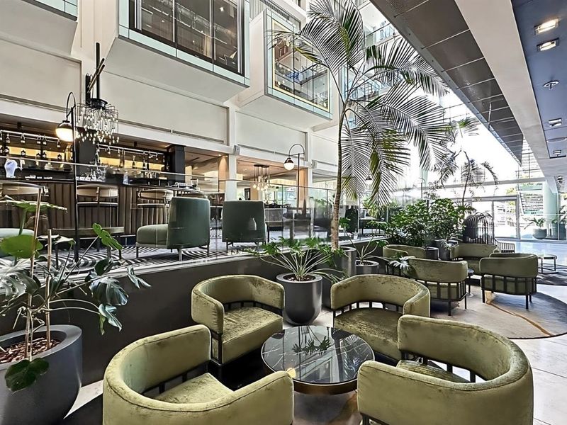 Sophisticated multi-level clubhouse area featuring a built-in bar, modern glass balustrades, and high-ceiling architectural design suitable for luxury penthouse living.
